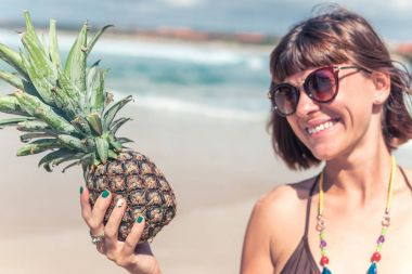 Ananas üzerinde seyir ve gülümseyen kadın tropikal yaz. Açık havada, okyanus, doğa. Bali Adası cennet.