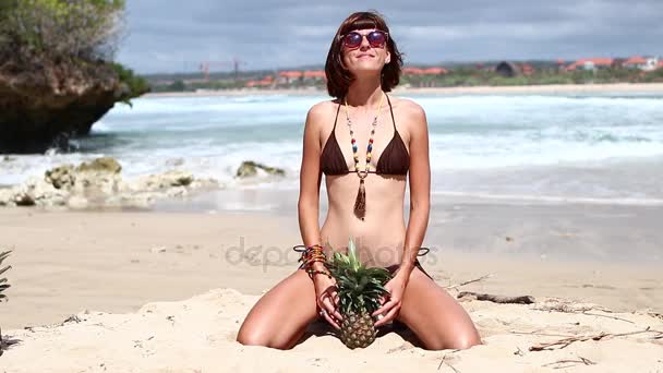Sexy vrouw in een bruin zwembroek op het strand met ananas. Jonge vrouwelijke zomervakantie genieten op een tropisch eiland Bali, Indonesië. — Stockvideo