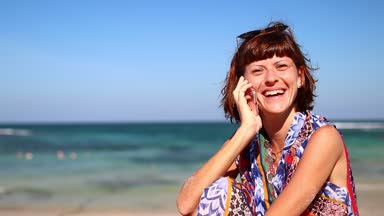 Kumsalda gülüyor mobil akıllı telefon kullanan kadın. Kız mutlu smartphone kullanarak bikini. Tropikal Bali Adası, Endonezya.