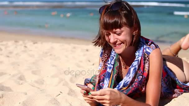 Γυναίκα χρησιμοποιώντας κινητό κινητό έξυπνο τηλέφωνο γέλιο στην παραλία. Κορίτσι στο μπικίνι χρησιμοποιώντας smartphone ευτυχισμένη. Τροπικό νησί Μπαλί, Ινδονησία. — Αρχείο Βίντεο