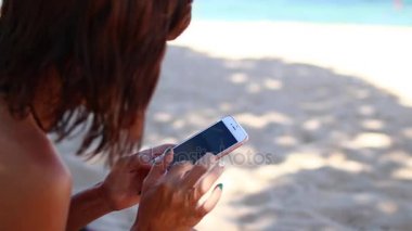 Kumsalda gülüyor mobil akıllı telefon kullanan kadın. Kız mutlu smartphone kullanarak bikini. Tropikal Bali Adası, Endonezya.