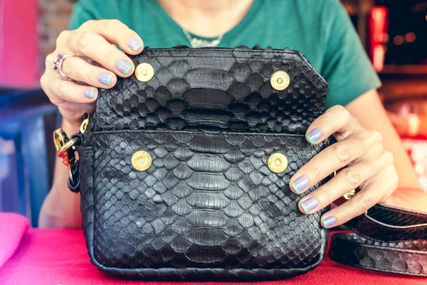 Fashion luxury snakeskin python handbag on the wooden table in restaurant. Bali island.