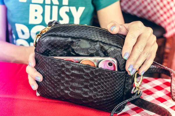 Fashion luxury snakeskin python handbag on the wooden table in restaurant. Bali island.