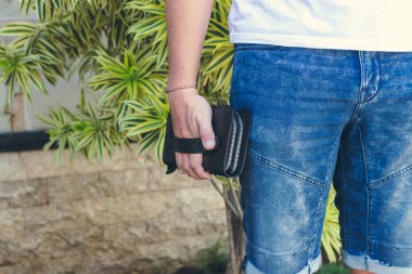 Adam tutarak el yapımı çanta egzotik deri yılan derisi python, açık havada, yeşil tropikal arka plan yaptı. Bali Adası.