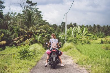 Mutlu kadın ormanda yağmur ormanlarında bir tropikal Bali Adası, Endonezya'nın bir motosiklet üzerinde. Özgürlük kavramı. Bayan bir scooter üzerinde.