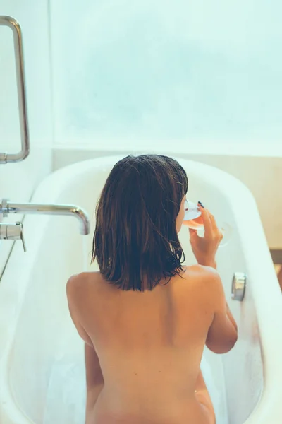 Femeie tânără atractivă cu sticlă de șampanie relaxantă în baie. Femeie sexy în baie. Femei spa . — Fotografie, imagine de stoc