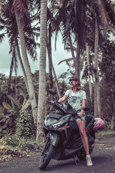 Молодая счастливая женщина на мотоцикле в джунглях тропических лесов острова Бали, Индонезия. Понятие свободы. Леди на скутере
.