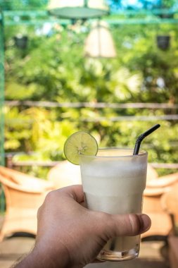 Bir bardak taze organik limon suyu güzel doğa arka plan üzerinde adam elinde. Bali Adası, Endonezya.