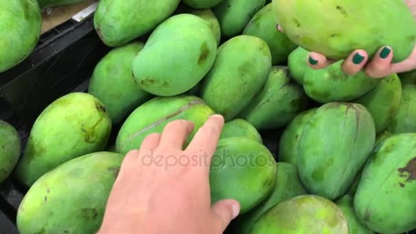 スーパーで新鮮な有機マンゴーを選ぶ男と女の手。食品のショッピング. — ストック動画