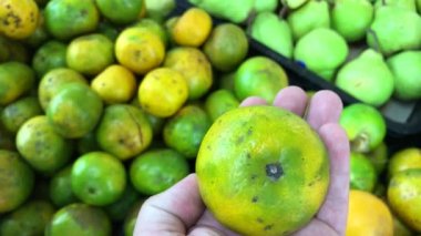 Asya çiftçi süpermarkette taze yeşil organik mandalina seçme adam.