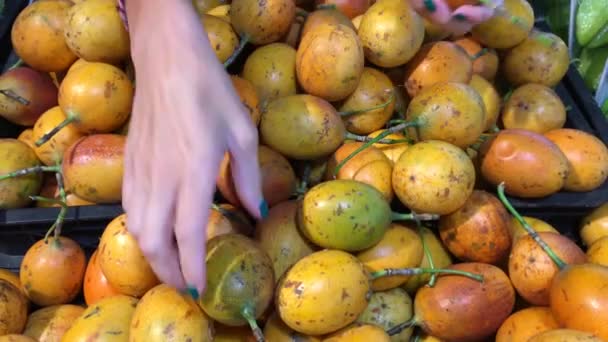 Vrouw hand selectie van verse biologische exotische passie fruit in de supermarkt. Zuid-Azië, Indonesië, Bali. — Stockvideo