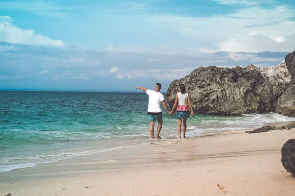 幸せな若い新婚旅行のカップルは、ビーチの上を歩きます。海、バリ島、インドネシアで熱帯の休暇. — ストック写真