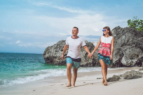 幸せな若い新婚旅行のカップルは、ビーチの上を歩きます。海、バリ島、インドネシアで熱帯の休暇. — ストック写真