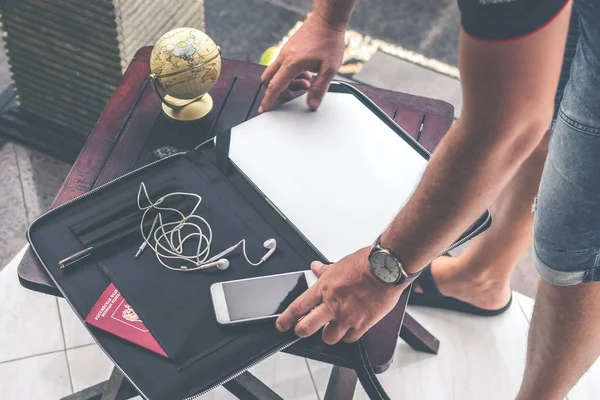 Mann mit luxuriöser Schlangenhaut-Python-Laptoptasche auf einem Tisch vor dem asiatischen Garten. Männermode Konzept. Laptoptasche. — Stockfoto