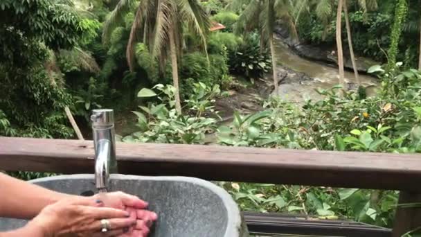 Frau wäscht ihre Hände draußen mit einem schönen tropischen Blick. Frische und Ökologie. bali-Insel. — Stockvideo