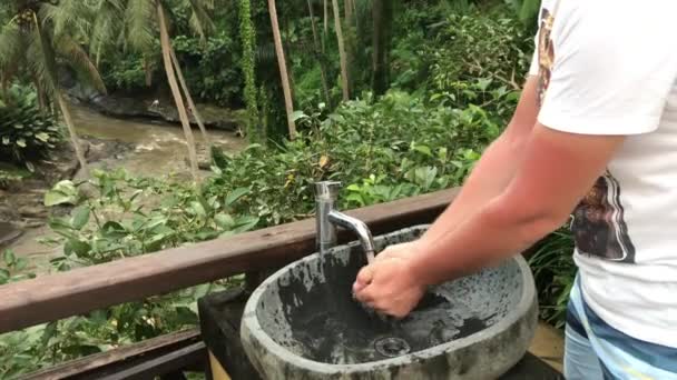 El hombre se lava las manos afuera con una hermosa vista tropical. Concepto de frescura y ecología. Isla de Bali . — Vídeo de stock