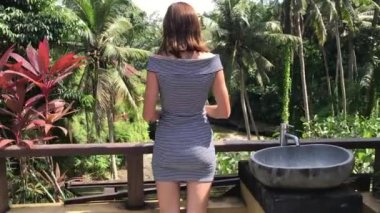 Genç, terasta ayakta ve nehirde seyir hoş kadın. Tropikal orman arka plan. Bali Adası.