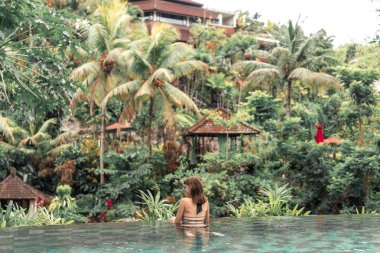 Mutlu genç kadın, bir tropikal sonsuzluk havuzunda. Lüks resort Bali Adası.
