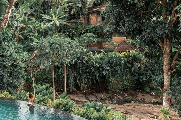 Glückliche junge Frau in einem tropischen Infinity-Pool. Luxusresort auf der Insel Bali. — Stockfoto