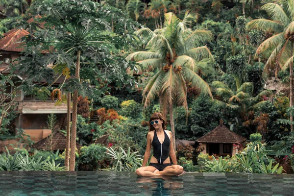 Gelukkig jonge vrouw in een tropische infinity pool. Luxeresort op het eiland Bali. — Stockfoto