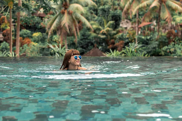 Gelukkig jonge vrouw in een tropische infinity pool. Luxeresort op het eiland Bali. — Stockfoto
