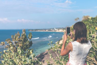Genç kadın güneşli gün Uçurumdaki okyanus güzel arka plan ile fotoğraf çekmek. Bali Adası.