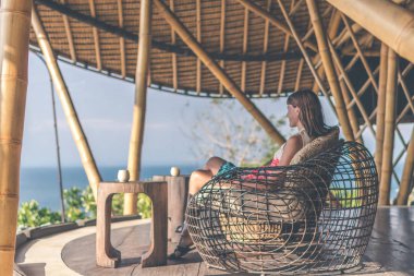 Bambu restoranda oturan kadın. Orijinal yer. Metin için yer. Bali Adası.