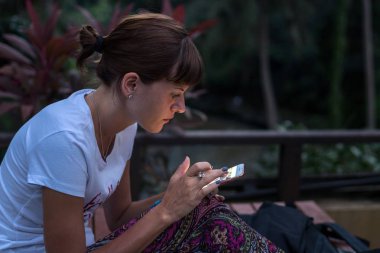 Smartphone açık havada gece kullanan genç kadın. Bali Adası.