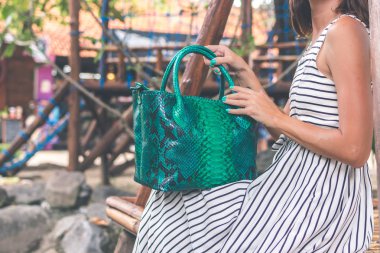 Kadın elleriyle lüks yılan derisi çanta açık havada. Tropikal moda egzotik kavramı.