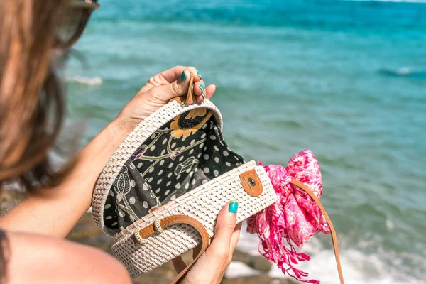 De handen van de vrouw met trendy stijlvolle witte rotan tas en zijde sjaal buiten. Tropische eiland Bali, Indonesië. Rotan handtas en zijden sjaal. — Stockfoto