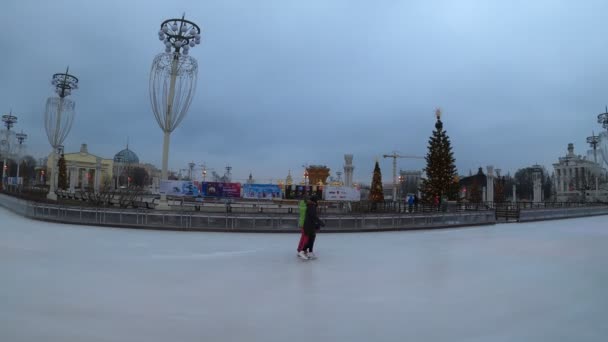 モスクワ,ロシア- 2019年11月27日:人々はVdnkhで大きな都市のアイススケートリンクに乗っています。過経過. — ストック動画