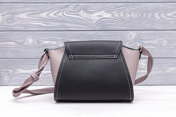Fashion synthetic leather black handbag on a wooden background. Eco leather.