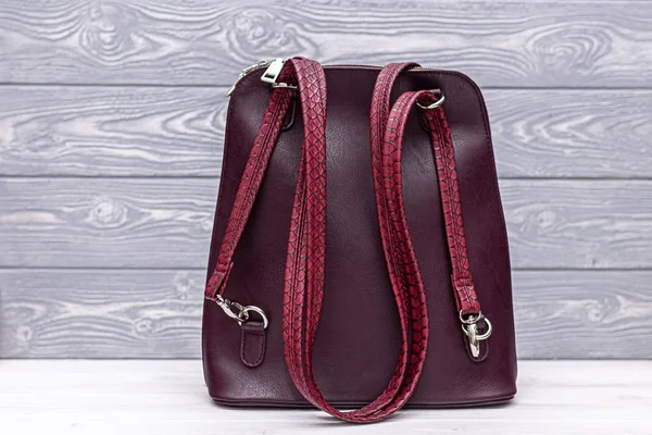 Synthetic leather red backpack on a wooden background. Eco leather bag.