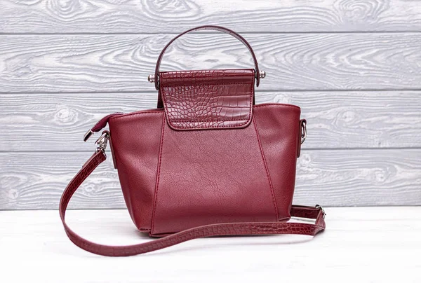 Fashion synthetic leather red handbag on a wooden background. Eco leather.