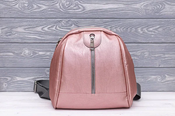 Synthetic leather pink backpack on a wooden background. Eco leather bag.