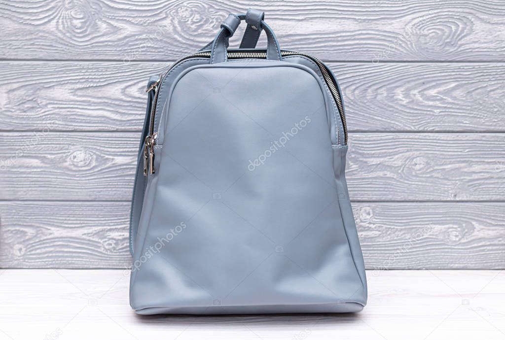 Synthetic leather blue backpack on a wooden background. Eco leather bag.