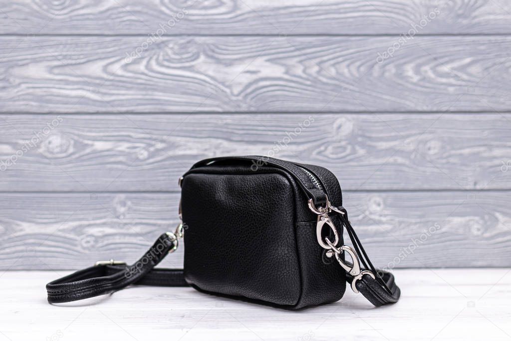 Fashion synthetic leather black handbag on a wooden background. Eco leather.