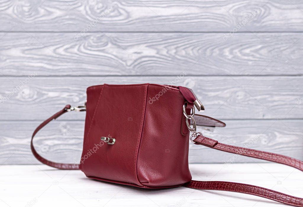 Fashion synthetic leather red handbag on a wooden background. Eco leather.