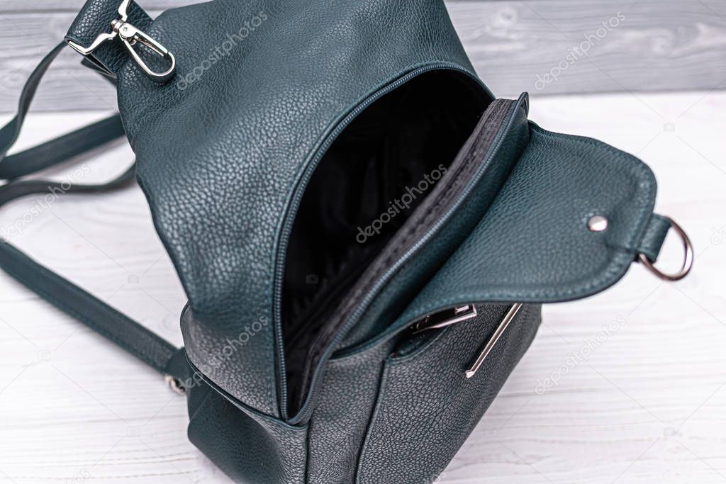 Synthetic leather green backpack on a wooden background. Eco leather bag.