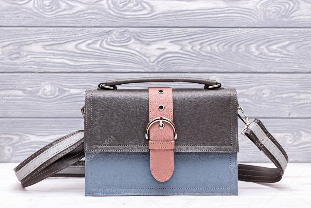 Fashion synthetic leather blue and grey handbag on a wooden background. Eco leather.