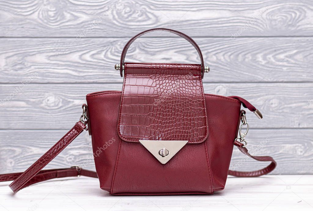 Fashion synthetic leather red handbag on a wooden background. Eco leather.