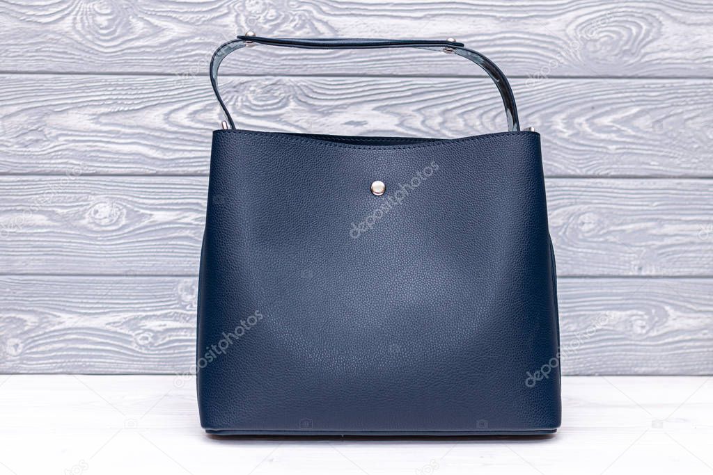 Fashion synthetic leather blue handbag on a wooden background. Eco leather.