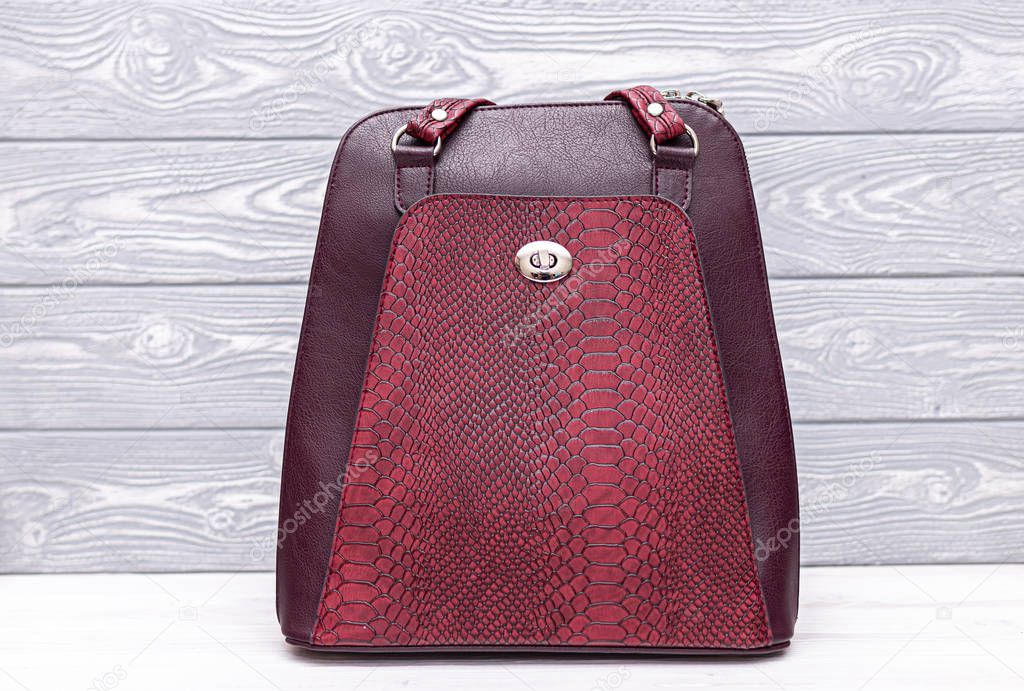 Synthetic leather red backpack on a wooden background. Eco leather bag.