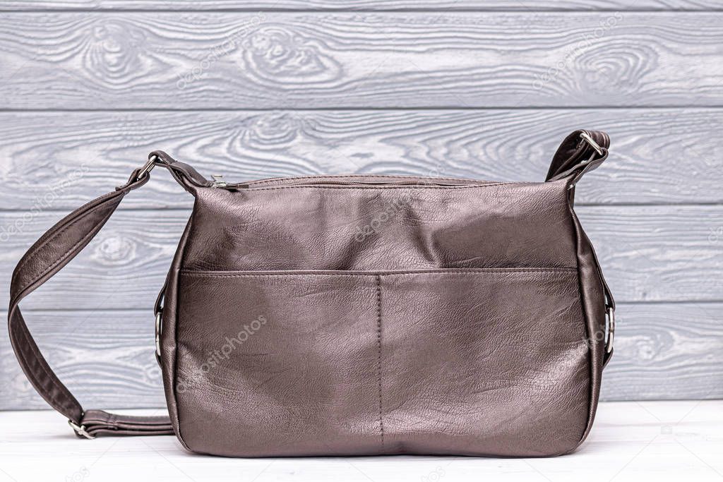 Fashion synthetic leather bronze handbag on a wooden background. Eco leather.