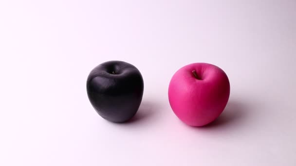 Dos manzanas aisladas sobre un fondo blanco. Rosa y negro manzana, extraño y divertido tiro . — Vídeos de Stock
