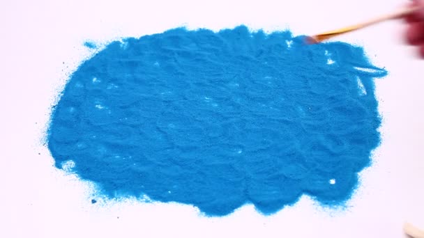 人的手在蓝色的艺术沙滩上写下了头号。白色背景的演播室镜头. — 图库视频影像