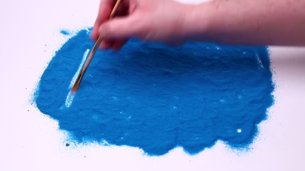 Man hand schrijft een woord Dream on a blue art sand. Studio beelden op een witte achtergrond. — Stockvideo