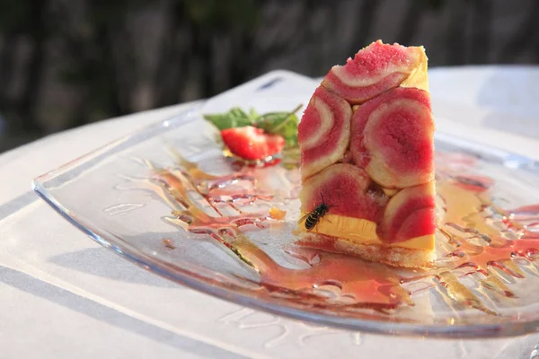 Piece of cake on a glass plate and a bee — Stock Photo, Image