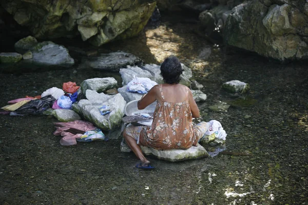 Filipino elderly woman washing clothes in the river. Philippines — Stock Photo, Image