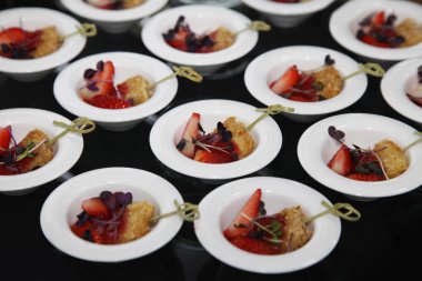 Büfede küçük bir tabakta taze çilekli küçük bir soya peyniri.